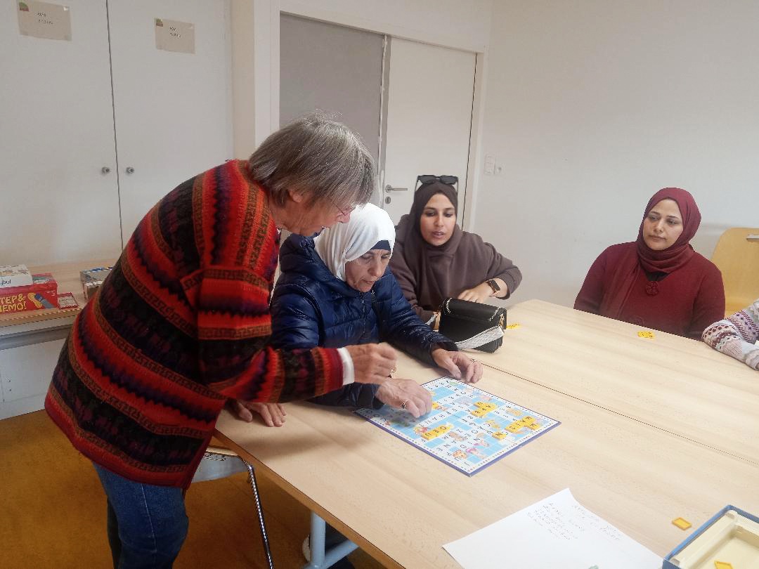 Une bénévole accompagne les apprenants dans un jeu de lettres.