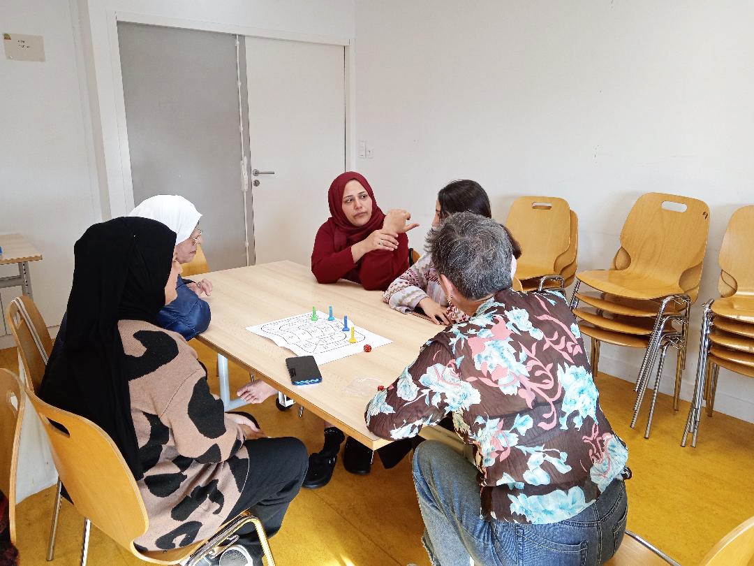 Apprenantes et bénévole échangent autour d’un jeu de société.
